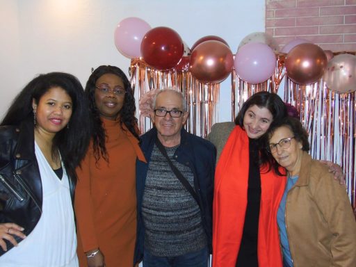 Cinq personnes souriantes posent ensemble devant des ballons et un décor festif.