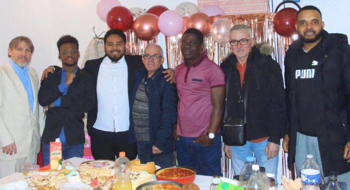 Groupe d'hommes souriants devant des décorations festives.