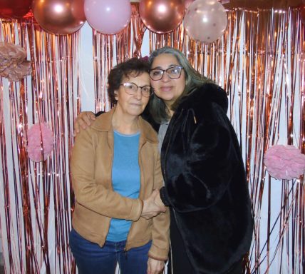 Deux femmes souriantes posent ensemble devant un décor de ballons et de frises.