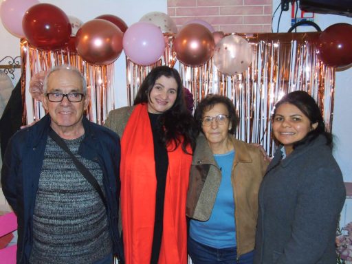 Quatre personnes souriantes devant un décor de fête avec des ballons et des guirlandes.